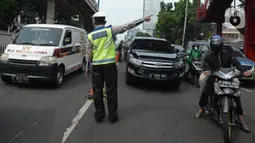 Petugas mengarahkan kendaraan saat penyekatan di ruas jalan Mampang Prapatan, Jakarta, Kamis (15/7/2021). Mampang menjadi salah satu jalan yang masuk dalam penyekatan baru pada Pemberlakuan Pembatasan Kegiatan Masyarakat (PPKM) darurat di Ibu Kota. (merdeka.com/Imam Buhori)