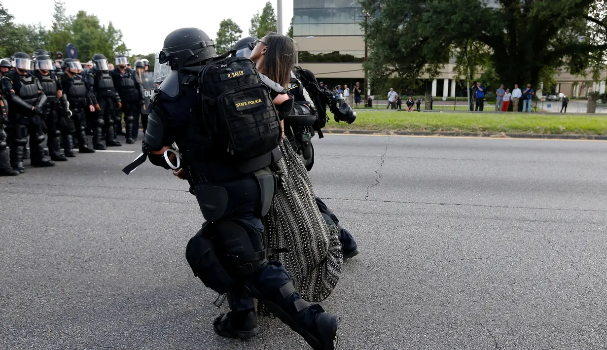 Polisi Anti Huru Hara AS menangkap seorang wanita yang melakukan unjuk rasa di dekat markas Kepolisian Rouge Baton di Baton Rouge, Louisiana, AS (9/7). Netizen mengagumi keberanian wanita tersebut. (REUTERS / Jonathan Bachman)
