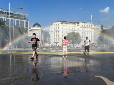 Anak-anak menyejukkan diri di dekat semprotan air di Schwarzenbergplatz di Wina, Austria (28/7/2020). Suhu tertinggi di Wina mencapai angka 37,2 derajat Celsius pada Selasa (28/7). (Xinhua/Guo Chen)