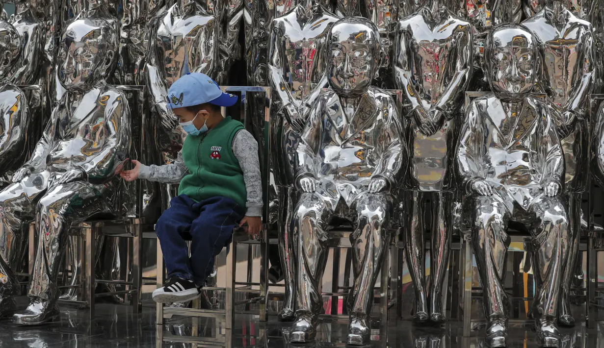 Seorang anak yang mengenakan masker untuk mengekang penyebaran COVID-19 memegang patung di Beijing, China, Minggu (11/10/2020). Meski penyebaran COVID-19 hampir diberantas di China, pandemi masih melonjak di seluruh dunia dengan jumlah kematian yang terus meningkat. (AP Photo/Andy Wong)
