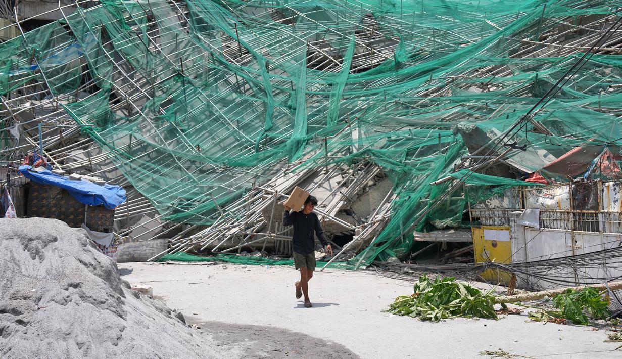Seorang pria melewati bangunan yang runtuh di kota Angeles, provinsi Pampanga, utara Manila, Filipina, Senin 25 Mei 2026. (AP Photo/Aaron Favila)