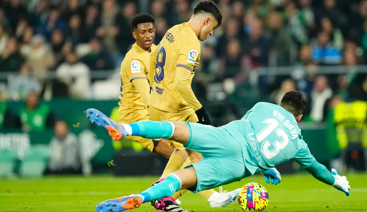 Kiper Real Betis Rui Silva melakukan penyelamatan di depan pemain Barcelona Pedri pada pertandingan sepak bola Liga Spanyol di Stadion Benito Villamarin, Seville, Spanyol, 1 Februari 2023. Barcelona genap mengoleksi 50 poin dan unggul 8 poin dari Real Madrid usai menang 2-1 atas Real Betis pada lanjutan Liga Spanyol. (AP Photo/Jose Breton)