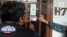 Petugas Pemutakhiran Data Pemilih (Pantarlih) menempelkan stiker pada jendela rumah warga saat melakukan pencocokan dan penelitian (coklit) data pemilih untuk Pemilu 2024 di rumah warga di Beki, Depok, Jawa Barat, Minggu  (26/2/2023). Komisi Pemilihan Umum (KPU) di semua wilayah Indonesia melakukan pencocokan dan penelitian (coklit) data pemilih dengan datang dari rumah ke rumah guna mengantisipasi ketidaksesuaian data Pemilu 2024. (merdeka.com/Arie Basuki)