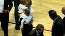 President Amerika Serikat Barack Obama menggendong anak-anak pada pembukaan NBA antara  Cleveland Cavaliers melawan Chicago Bulls di Chicago, Selasa(27/10/2015). (REUTERS / Jonathan Ernst)