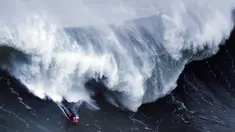 Seorang peselancar bersiap menyambut kejaran ombak besar dibelakangnya saat berselancar di Praia do Norte di Nazare, Portugal (19/11). Selancar merupakan sebuah olahraga yang dilakukan di atas ombak yang tinggi. (AFP/Patricia De Melo Moreira)