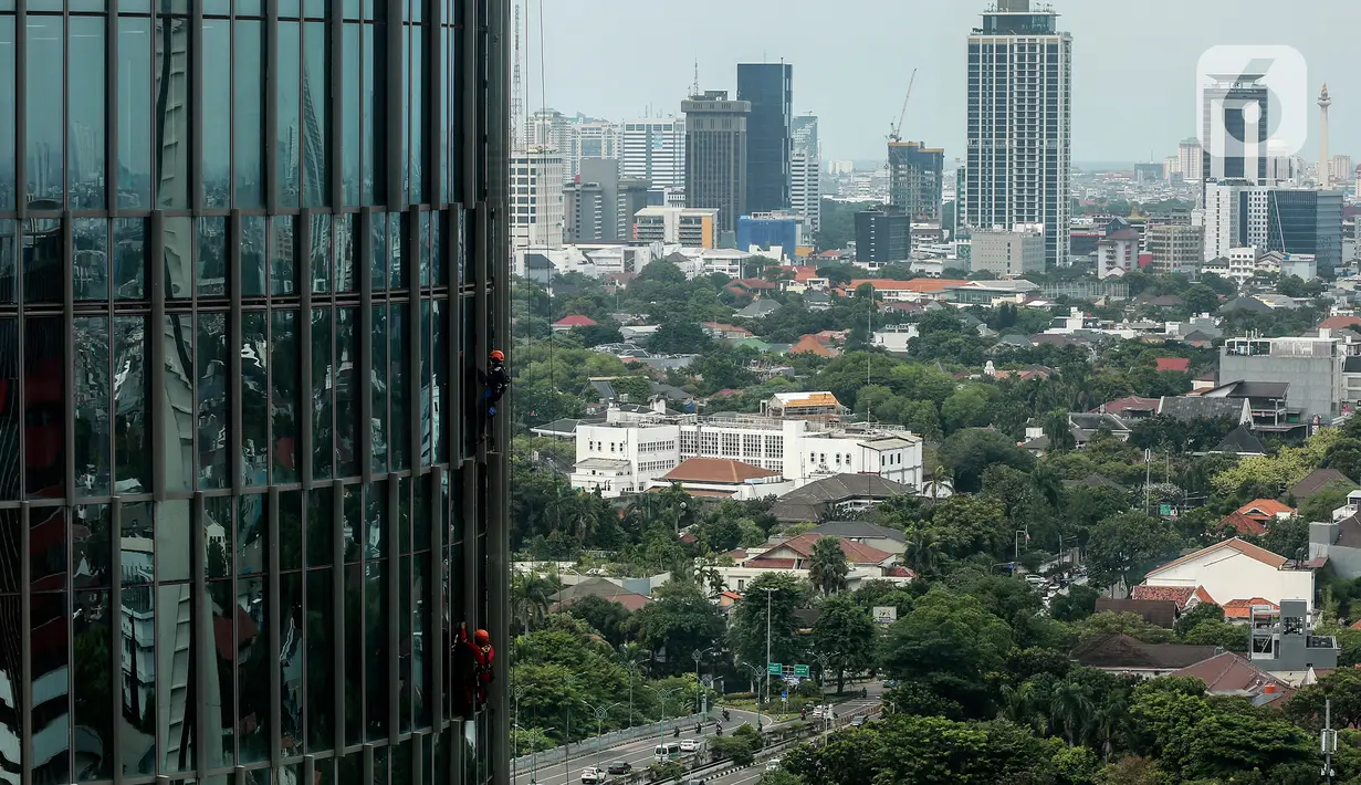 Pekerja bergelantungan membersihkan bagian luar gedung di kawasan Kuningan, Jakarta, Minggu (19/12/2021). Pekerja ini harus bergelantungan dengan seutas tali untuk membersihkan dinding-dinding gedung bertingkat yang tingginya kurang lebih mencapai 150 meter. (Liputan6.com/Johan Tallo)