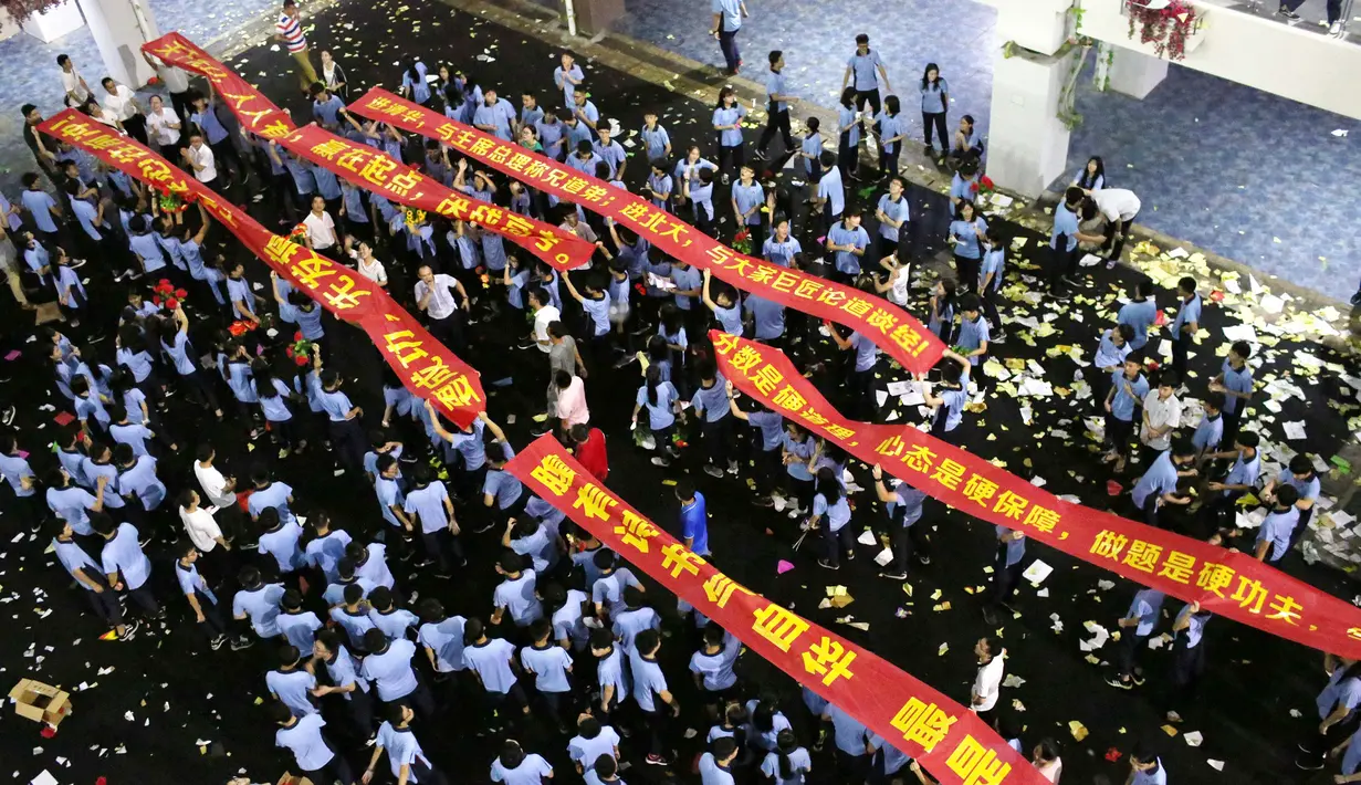 Sejumlah siswa berbaris sambil membentengkan spanduk saat melukan parade untuk menghilangkan stres jelang ujian tahunan "Gaokao" di Haikou, China (4/6). (AFP)