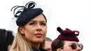 Dua wanita menunggu untuk menyaksikan dimulainya balapan pada hari pertama Festival Cheltenham di Cheltenham Racecourse, di Cheltenham, Inggris (15/3/2022). Festival empat hari berlangsung setiap tahun pada bulan Maret di Cheltenham Racecourse di Cheltenham, Gloucestershire. (AFP/Adrian Dennis)