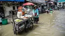 Pedagang sayur berjualan saat banjir rob di kawasan Muara Angke, Jakarta, Selasa (9/11/2021). Badan Penanggulangan Bencana Daerah (BPBD) DKI Jakarta memperkirakan puncak musim hujan dan potensi rob di Ibu Kota terjadi pada Januari hingga Februari 2022. (Liputan6.com/Faizal Fanani)