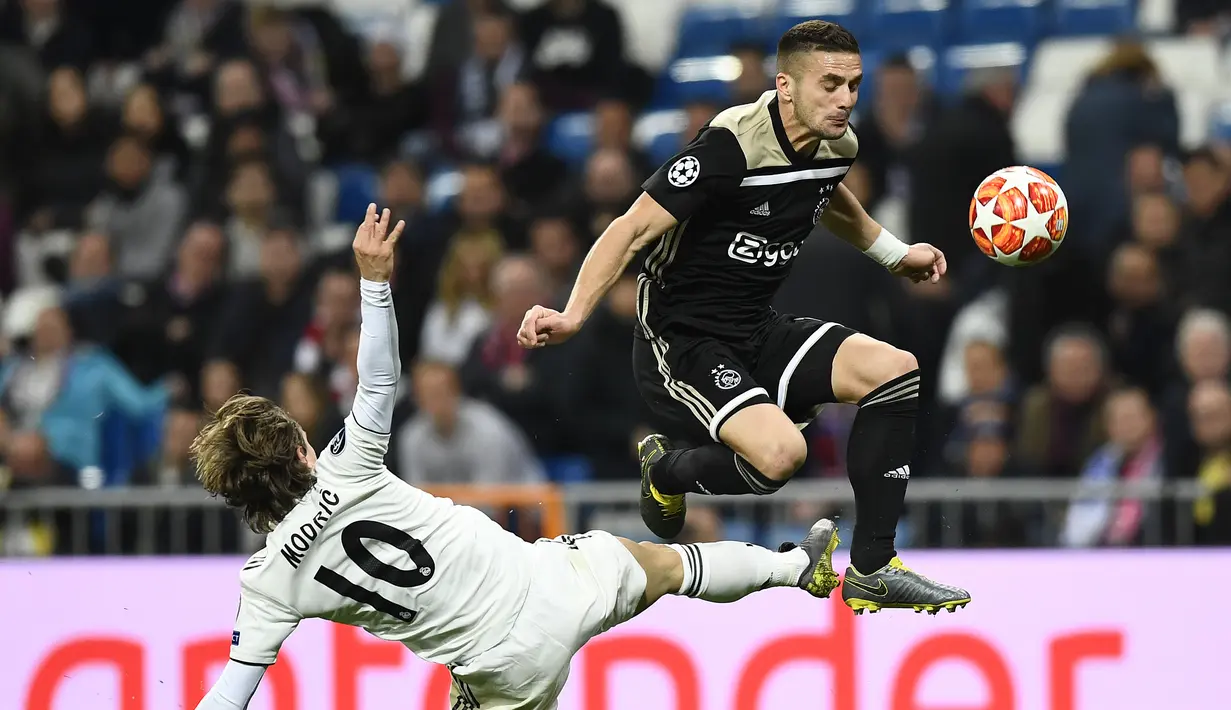 Dusan Tadic mencoba melewati hadangan Luka Modric pada laga leg kedua, babak 16 besar Liga Champions yang berlangsung di Stadion Santiago Bernabeu, Madrid, Rabu (6/3). Real Madrid kalah 1-4 kontra Ajax. (AFP/Gabriel Bouys)