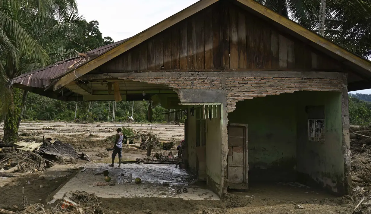 Seorang warga desa melihat-lihat dari rumahnya yang rusak akibat banjir bandang di Garoga, Provinsi Sumatera Utara, pada Kamis 4 Desember 2025. (YT HARIONO/AFP)