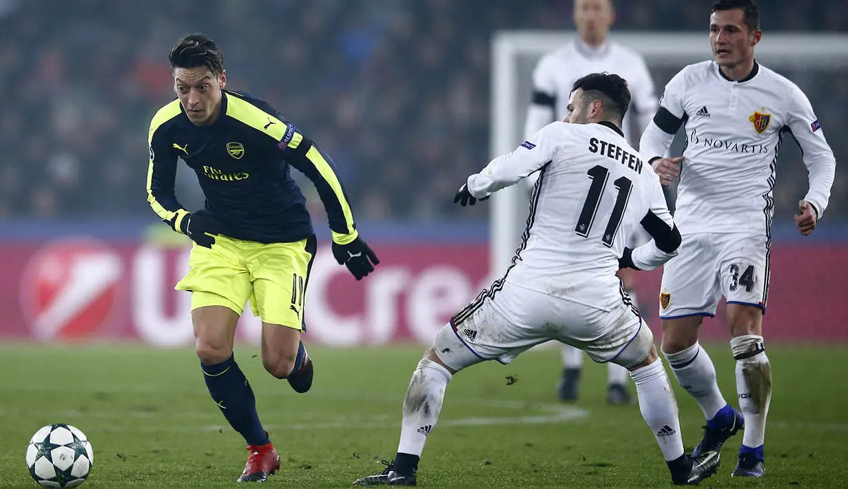 Gelandang Arsenal, Mesut Ozil, berusaha melewati hadangan pemain FC Basel, Renato Steffen. Meski berstatus tamu, Arsenal lebiih menguasai jalannya laga dengan penguasaan bola 55 persen. (Reuters/Andrew Couldridge)