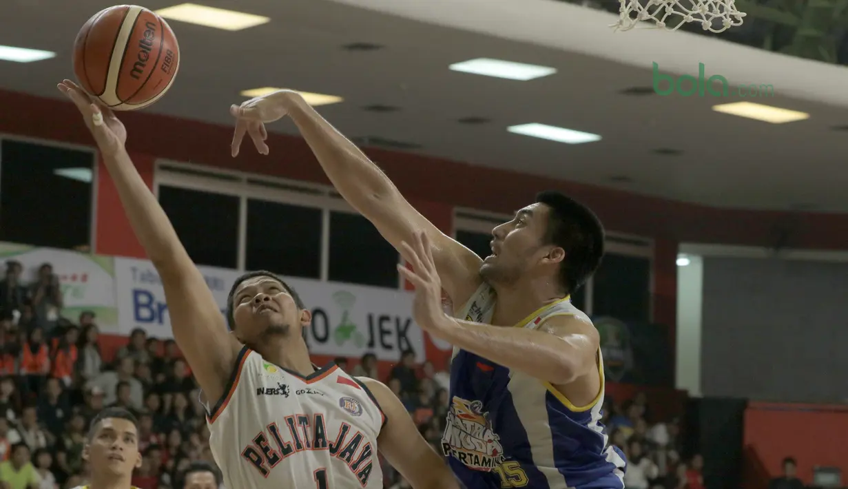 Pemain Satria Muda, Christian Sitepu (kanan) mencoba menghalau bola tembakan pemain Pelita Jaya, Andrie Ekayan pada Final IBL 2018 di GOR Sumantri Brojonegoro, Jakarta, Minggu (22/4/2018). Satria Muda menang 69-64. (Bola.com/Nick Hanoatubun)