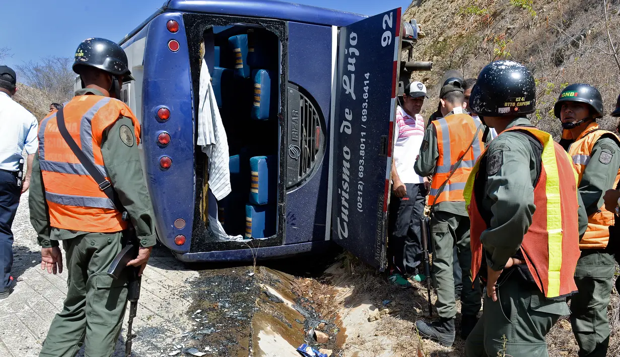 Sejumlah petugas mengamati sebuah bus yang terbalik di jalan raya Caracas-La Guaira, Venezuela, Rabu (10/2). Bus yang mengangkut pemain tim sepak bola Argentina Huracan itu terbalik saat menuju Bandara Internasional Simon Bolivar. (AFP/FEDERICO PARRA)