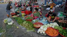 Pedagang menyiapkan sayuran untuk dijual di sepanjang jalan karena pasar tetap tutup di tengah pembatasan lockdown yang diberlakukan untuk mencoba menghentikan lonjakan kasus virus corona COVID-19 di Phnom Penh, Kamboja, Selasa (11/5/2021). (TANG CHHIN Sothy/AFP)