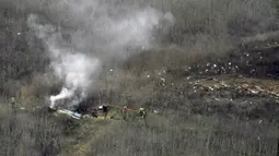 Petugas pemadam kebakaran berusaha memadamkan api di lokasi kecelakaan helikopter yang ditumpangi pebasket NBA Kobe Bryant di sisi bukit di Calabasas, California (26/1/2020). Selain Bryant, empat orang lainnya dalam helikopter itu juga dinyatakan meninggal dunia. (AP Photo/Mark J. Terrill)