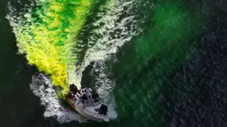 Petugas menggunakan kapal untuk menyemprotkan pewarna  hijau khusus ke sungai Chicago, AS selama perayaan St. Patrick's Day, 11 Maret 2017. Sungai itu setiap tahun mengalami perubahan warna demi memikat wisatawan. (John J. Kim/Chicago Tribune melalui AP)