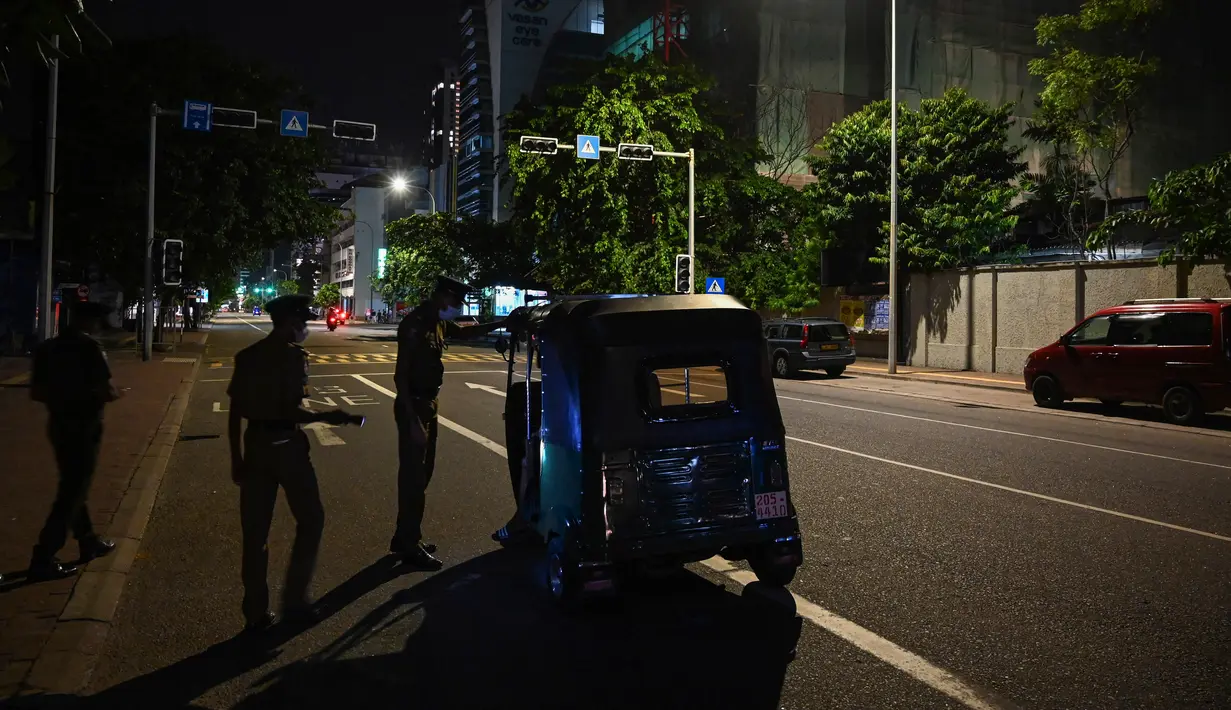 Polisi berbicara dengan penumpang bajaj di tengah jam malam 36 jam mencegah protes terhadap Presiden Sri Lanka Gotabaya Rajapaksa di Kolombo, 2 April 2022. Perintah datang sehari usai pemberlakukan keadaan darurat menyusul protes keras atas krisis ekonomi terburuk negara itu (Ishara S. KODIKARA/AFP)