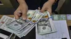 Seorang menghitung uang kertas Dolar AS di salah satu kantor penukaran uang, Jakarta, Selasa 12 Mei 2026. Nilai tukar rupiah terhadap dolar Amerika Serikat (USD) terpuruk pada perdagangan Selasa (12/5/2026). (BAY ISMOYO/AFP)