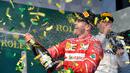 Pembalap Ferrari, Sebastian Vettel menyemprotkan sampanye di atas podium setelah berhasil memenangi balapan GP Australia di Sirkuit Albert Park, Melbourne, Minggu (26/3). Vettel sukses mengasapi rival utamanya Lewis Hamilton. (AP Photo/Andy Brownbill)