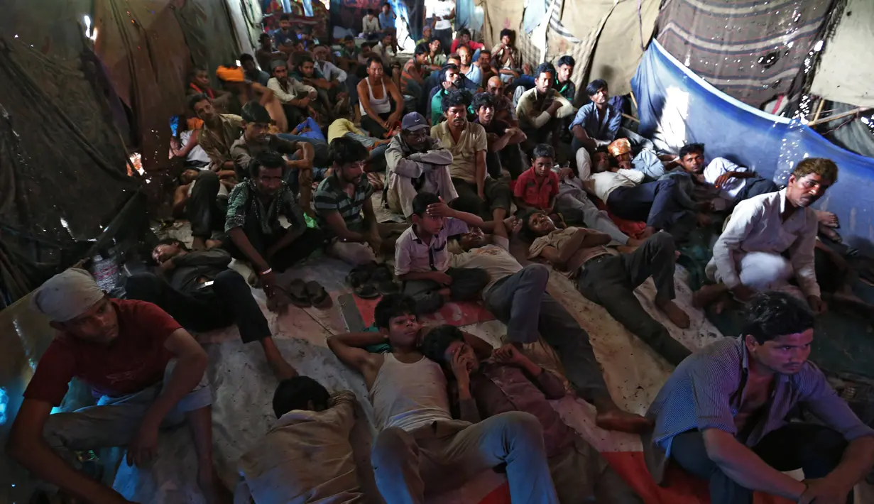 Sejumlah orang serius menonton film di bioskop darurat yang terletak di bawah jembatan di kuartal tua Delhi, India (25/5). Bioskop ini menampilkan berbagai film dan musik India dengan menggunakan sebuah televisi. (REUTERS/Cathal McNaughton)