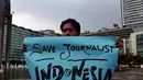 Seorang wartawan membentangkan poster saat aksi solidaritas tolak kekerasan terhadap jurnalis di Bundaran HI, Jakarta, Jumat (14/11/2014). (Liputan6.com/Johan Tallo)