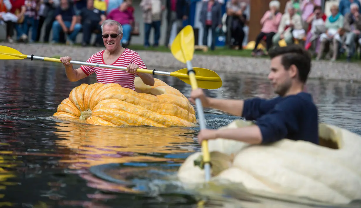 Juergen Herrmann dan Christoph Zimmermann berpartisipasi dalam lomba tradisional mendayung buah labu di Fambach, Jerman, Minggu (10/9). Perlombaan melibatkan beberapa perahu dari labu raksasa, dalam jalur sepanjang 200 meter. (Jens-Ulrich Koch/dpa via AP)