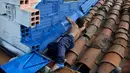 Seorang anak melukis dinding bangunan di kawasan kumuh El Pesebre, pinggiran kota Medellin, Kolombia, 19 Juni 2017. Seniman Prancis, Tarik Bouanani melukis 230 rumah di kawasan tersebut membentuk mural raksasa. (JOAQUIN SARMIENTO/AFP)