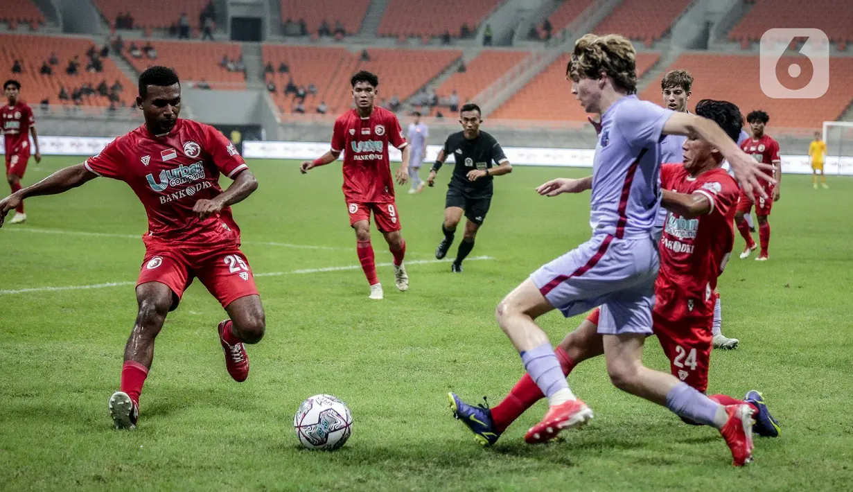 Pemain Indonesia All Star U-20 Salmani (kanan) dan Jimmy Julianus Aronggear (kiri) berebut bola dengan pemain FC Barcelona U-18 pada pertandingan International Youth Championship 2021 di Jakarta International Stadium, Jakarta, Rabu (13/4/2022). (Liputan6.com/Faizal Fanani)