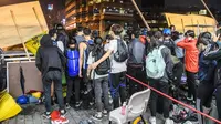 Demonstran antre menuruni jembatan menggunakan tali untuk melarikan diri dari Universitas Politeknik Hong Kong di Distrik Hung Hom, Hong Kong, Senin (18/11/2019). Lusinan demonstran melarikan diri dari Universitas Politeknik Hong Kong yang dikepung polisi selama berhari-hari. (ANTHONY WALLACE/AFP)