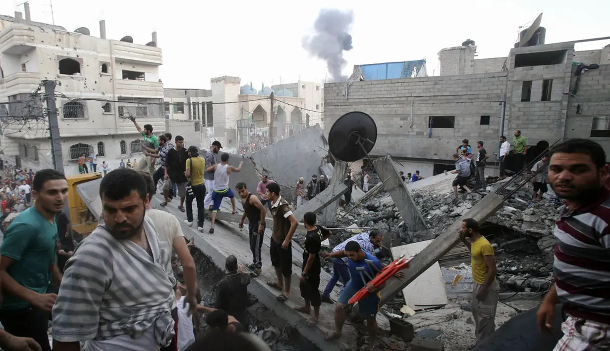 Beberapa warga Palestina berusaha mencari korban yang terjebak reruntuhan bangunan yang hancur akibat serangan udara militer Israel di kota Rafah, Palestina, (11/7/2014). (REUTERS/Ibraheem Abu Mustafa)