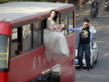Pesulap Lei Xin (kanan) berada di luar bus tingkat sambil melayang dengan seorang wanita bergaun pengantin di Zhengzhou, Provinsi Henan, China, (15/10/2015). Aksi bertujuan mengajak masyarakat untuk tidak takut menikah diusia muda. (REUTERS/Stringer)