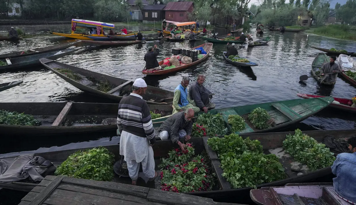 Laki-laki Kashmir menjual produk mereka di pasar sayuran terapung di Danau Dal, Srinagar, Kashmir yang dikuasai India, Kamis (7/4/2022). (AP Photo/Rajesh Kumar Singh)