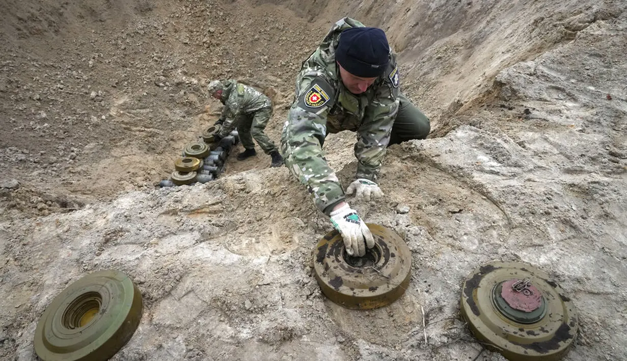 Pencari ranjau dari Kementerian Dalam Negeri Ukraina mengumpulkan bahan peledak pada sebuah lubang untuk meledakkannya dekat ladang ranjau di Desa Moshchun, dekat Kiev, Ukraina, 19 April 2022. (AP Photo/Efrem Lukatsky)