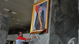 Petugas membersihkan foto presiden Joko widodo yang baru dipasang di pilar Gedung Nusantara III Kompleks Parlemen Senayan, Selasa (23/12/2014). (Liputan6.com/Andrian M Tunay)
