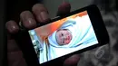 Vokalis Ada Band, Donnie Sibarani saat menunjukan foto bayi laki-lakinya yang lahir pada 18 April lalu di RS Bersalin Asih dan diberi nama Kent Leopold Sibarani, Jakarta, Selasa (21/4/2015). (Liputan6.com/Faisal R Syam)