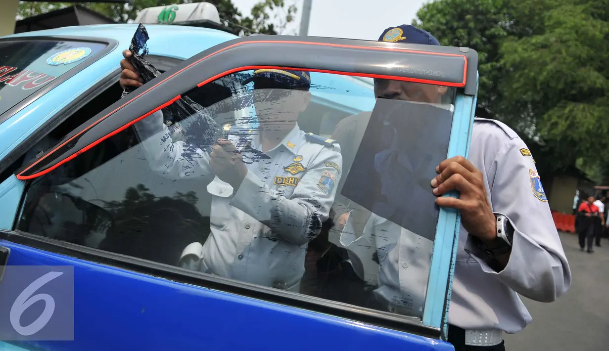 Petugas Dishub mencopot kaca film saat menggelar operasi uji kelengkapan surat kendaraan angkutan umum di Terminal Pasar Minggu, Senin (26/10/2015). Kegiatan ini untuk meningkatkan kapasitas pelayanan terhadap angkutan umum. (Liputan6.com/Gempur M Surya)
