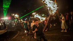 Seorang Pria bergembira saat membawa obor di Xichang, Provinsi Sichuan, China, (27/7). Festival obor ini untuk memperingati pegulat legendaris Atilaba yang mengusir wabah belalang menggunakan obor yang terbuat dari pinus pohon. (AFP PHOTO/FRED Dufour)