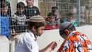 Anak-anak Palestina menyaksikan warga Yahudi merayakan Hari Purim di Jalan al-Shuhada, Kota Hebron, Tepi Barat, Kamis (1/3). Hari Purim diperingati untuk memperingati pembebasan orang-orang Yahudi dari genosida Persia kuno. (AFP PHOTO/HAZEM BADER)