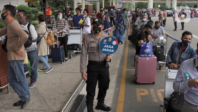 Polisi mengingatkan jaga jarak saat calon penumpang mengntre untuk rapid test antigen di Terminal 2 Bandara Soekarno-Hatta, Tangerang, Banten, Selasa (22/12/2020). Layanan rapid test antigen dibanderol dengan harga Rp 200 ribu. (merdeka.com/Arie Basuki)