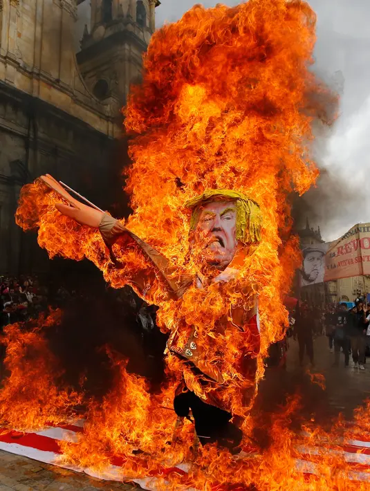 Para pengunjuk rasa membakar patung karakter Presiden AS Donald Trump saat melakukan aksi protes pada peringatan Hari Buruh di Bogota, Kolombia (1/5). Mereka melakukan aksi dengan membakar patung Donald Trump. (AP/Fernando Vergara)