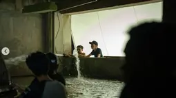 Para kru bergotong royong menciptakan adegan banjir di rusun lantai dasar. (Foto: Instagram/ jokoanwar)