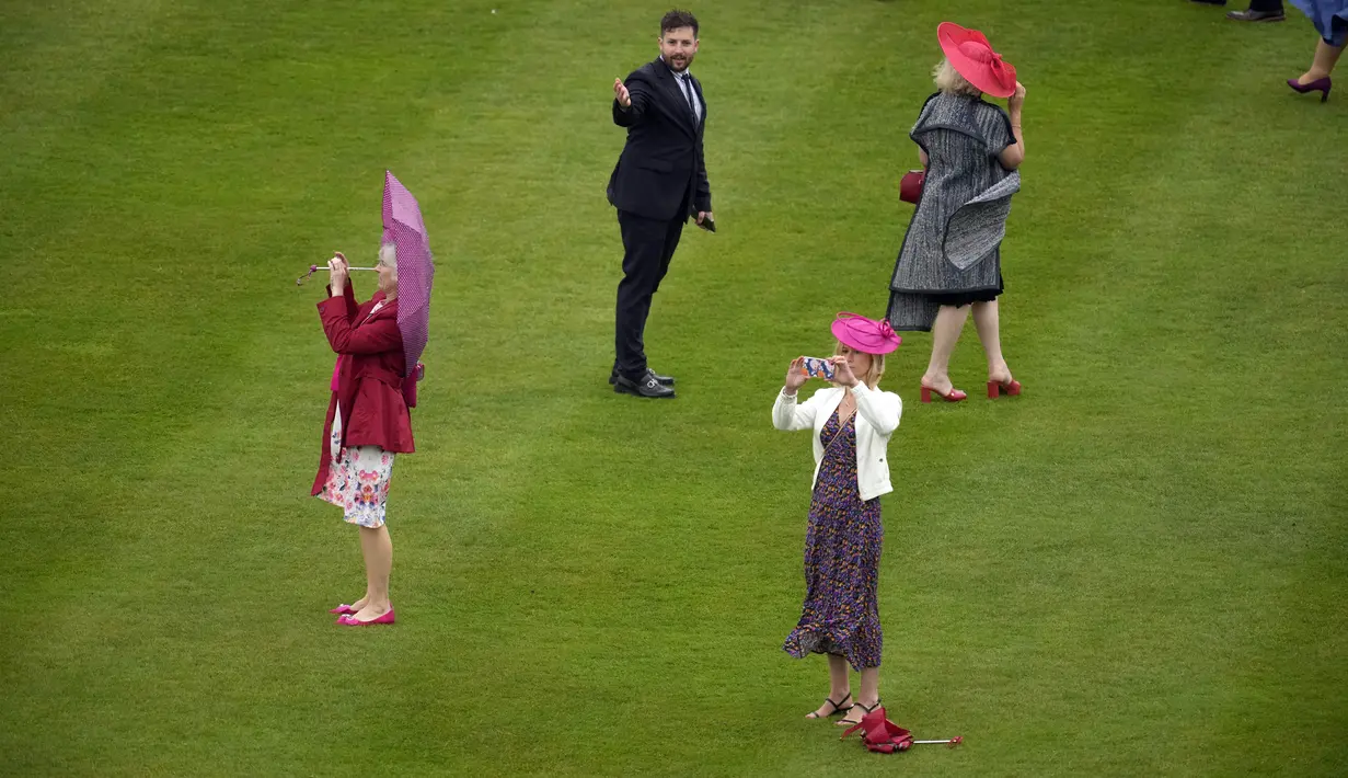 Para tamu menghadapi angin dan hujan saat mereka menghadiri pesta kebun pertama musim ini di Istana Buckingham, London, Inggris, 11 Mei 2022. Ratu Inggris Elizabeth II akan melewatkan musim pesta kebun kerajaan tradisional di mana dia biasanya bertemu dengan ratusan orang di halaman kediamannya di London dan Edinburgh. (AP Photo/Matt Dunham, Pool)