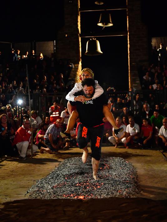 Sepasang kekasih berjalan di atas bara api selama malam San Juan di San Pedro Manrique, Spanyol Utara, Minggu (24/6). Tradisi kuno Spanyol ini diperingati untuk menyambut musim panas. (AP Photo/Alvaro Barrientos)