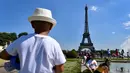 Warga berjemur di samping air mancur di Trocadero Esplanade, dekat Menara Eiffel, Paris (8/5). Seluruh situs di tempat ini dulunya adalah taman tua Palais du Trocadéro, yang ditata oleh Jean-Charles Alphand. (AFP Photo/Gerard Julien)