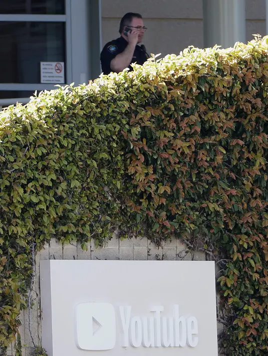 Petugas kepolisian berdiri di pintu masuk kantor pusat YouTube sesaat setelah insiden penembakan di San Bruno, California, Amerika Selatan, Selasa (3/4). Penegak hukum telah menyisir seluruh area bangunan untuk memastikan situasi telah aman (AP/Jeff Chiu)