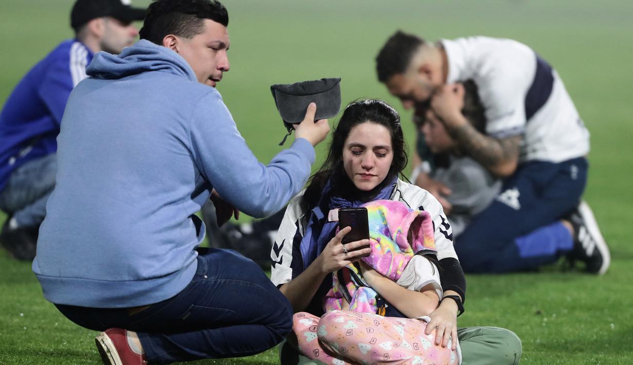 Sejumlah keluarga yang hadir di Stadion Juan Carmelo Zerill berusaha menenangkan kerabatnya usai kejadian penembakan gas air mata yang membuat pertandingan dihentikan sementara. (AFP/Alejandro Pagni)