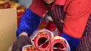 Seorang pekerja mengemas lentera merah menjelang perayaan Tahun Baru Imlek 2020 di sebuah pabrik di Wuyi, China, Kamis (26/12/2019). Beberapa keunikan pada tradisi perayaan Imlek yang masih dijalani warga Tionghoa adalah menggantung lentera merah. (Photo by STR / AFP)