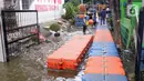 Petugas membuat jembatan apung saat banjir melanda Perumahan Periuk Damai, Tangerang, Banten, Selasa (23/2/2021). Adanya jembatan apung mempermudah warga saat melintasi banjir setinggi 2,5 meter di tempat tersebut. (Liputan6.com/Angga Yuniar)