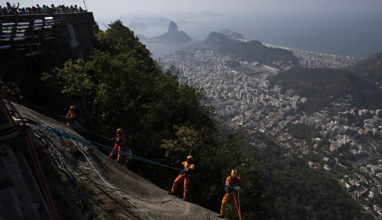 Kru pembersih Brasil melakukan panjat tebing di bawah bayang-bayang salah satu situs paling terkenal di dunia: Patung Kristus Sang Penebus di Rio de Janeiro. (AP Photo/Bruna Prado)